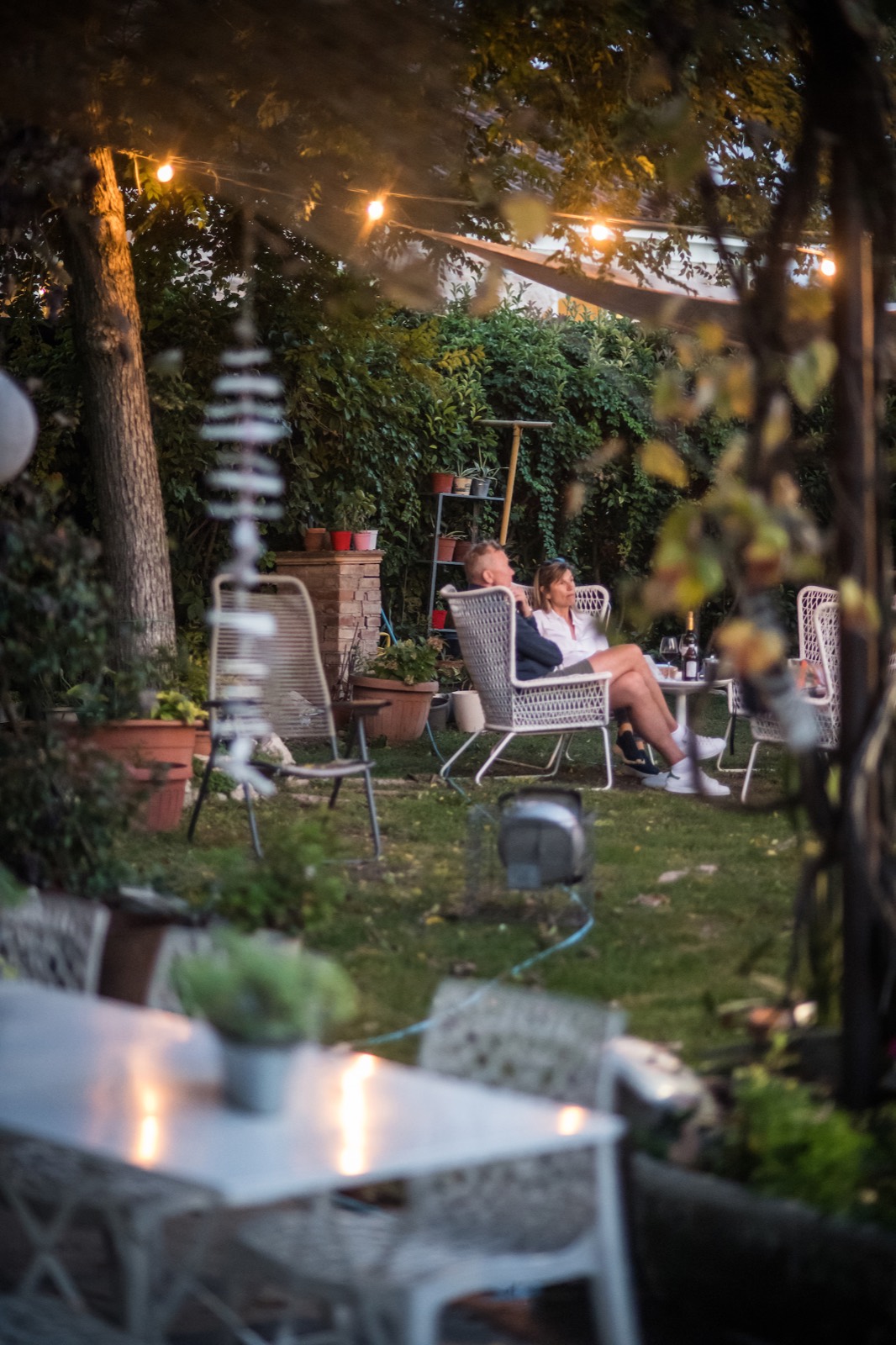 Ospiti rilassati in giardino tra le luci della sera, con un calice di vino