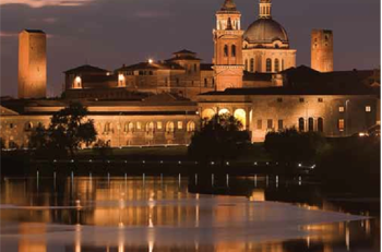 Lo skyline di Mantova illuminato al tramonto, riflesso sui laghi
