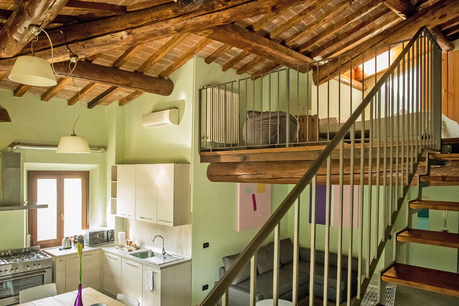 Il Loft Country: appartamento rustico con soppalco, soffitto a travi di legno, angolo cottura, salotto e scala in legno e ferro