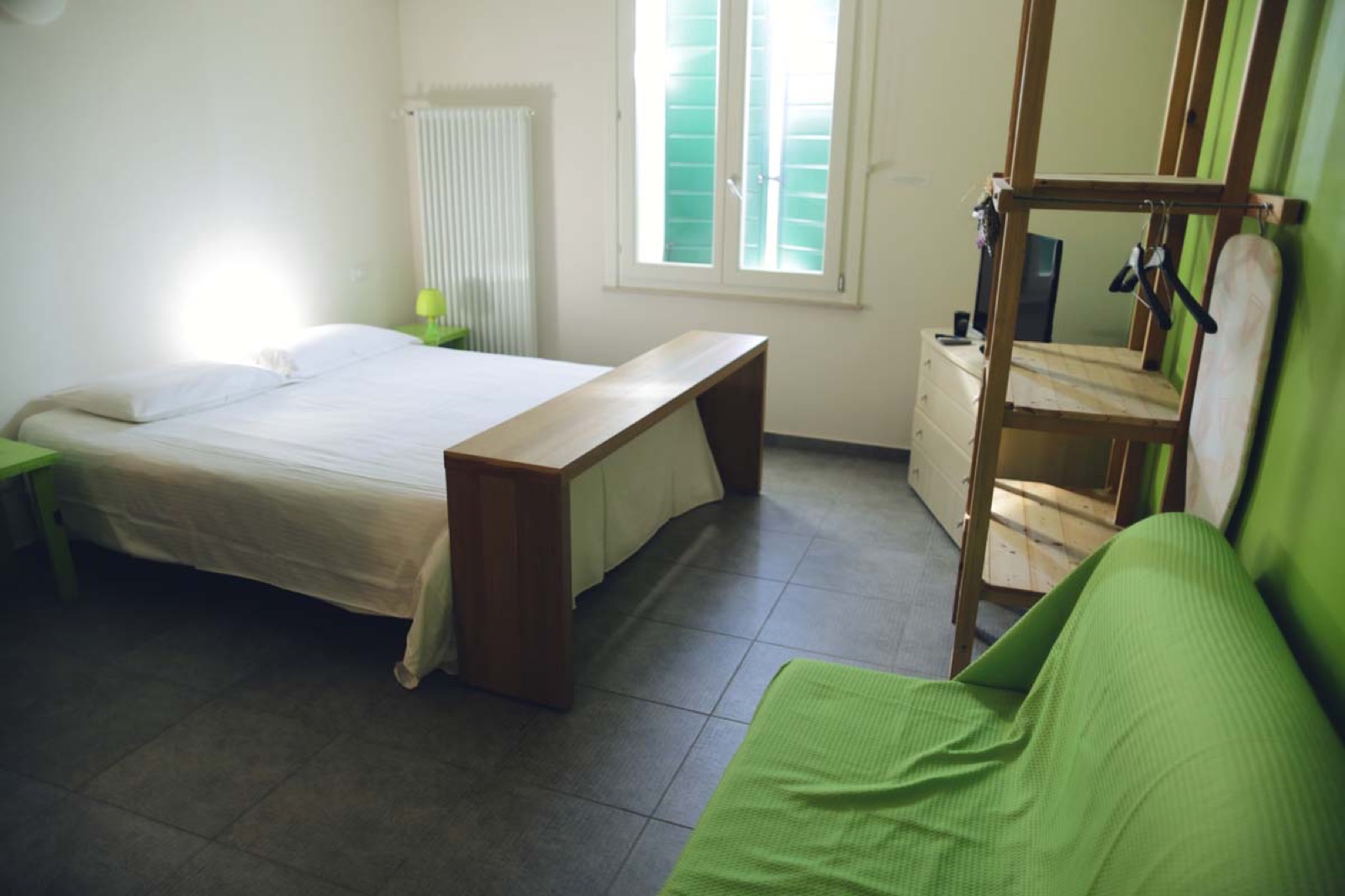 La Camera Mela Verde: letto bianco, divano e parete color verde mela, panca e arredi in legno di recupero, lampada verde